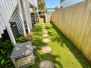 A narrow pathway with stepping stones leading to a wooden fence.