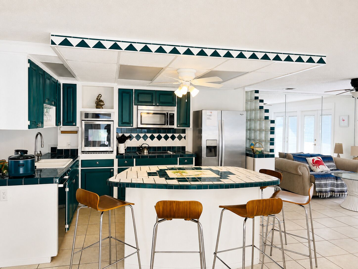 Een moderne keuken met een centraal eiland, barstoelen en een koelkast.