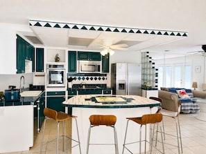 A modern kitchen with a central island, bar stools, and a refrigerator. - Cozy Coastal Retreat with Private Heated Pool Walk to Florida's Best Beaches (Destin)