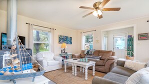 Ein Wohnzimmer mit einem weißen Sofa, einem braunen Sofa, einem weißen Couchtisch und einem Deckenventilator.