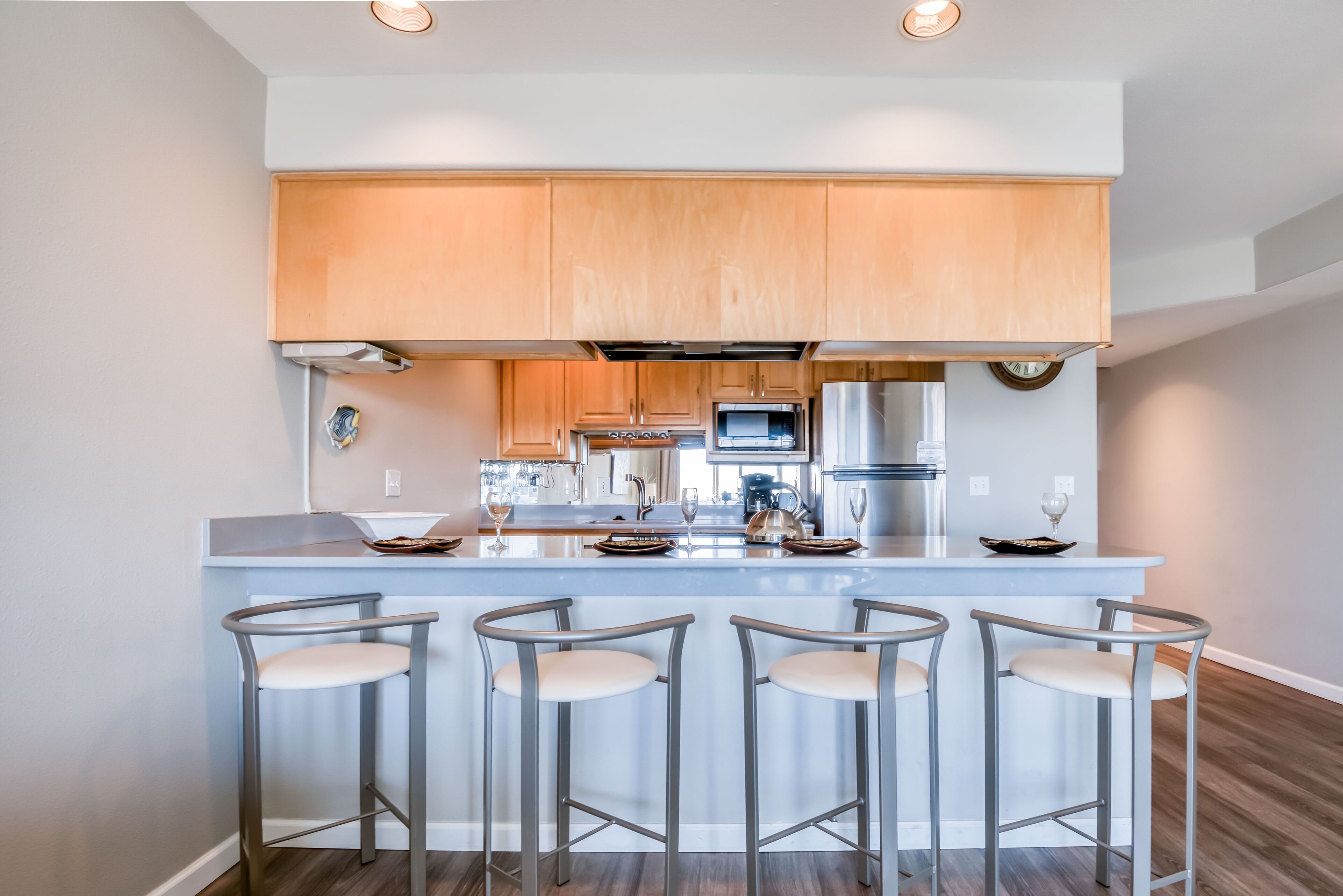 Una cocina moderna con armarios de madera, una isla central con taburetes de bar y electrodomésticos integrados.