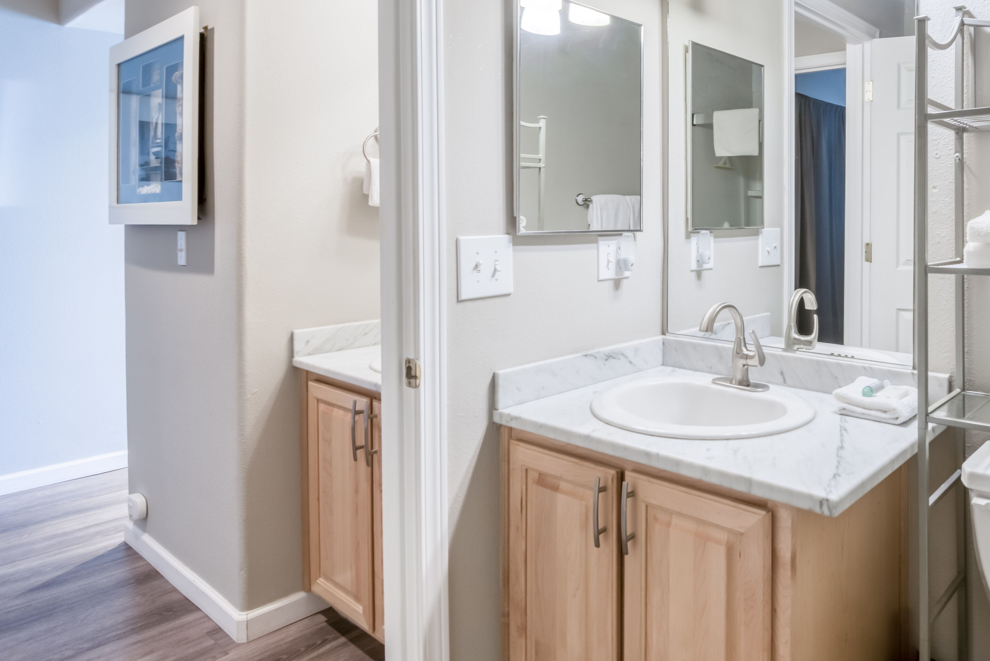 A modern bathroom with a marble sink, wooden cabinets, and a large mirror.