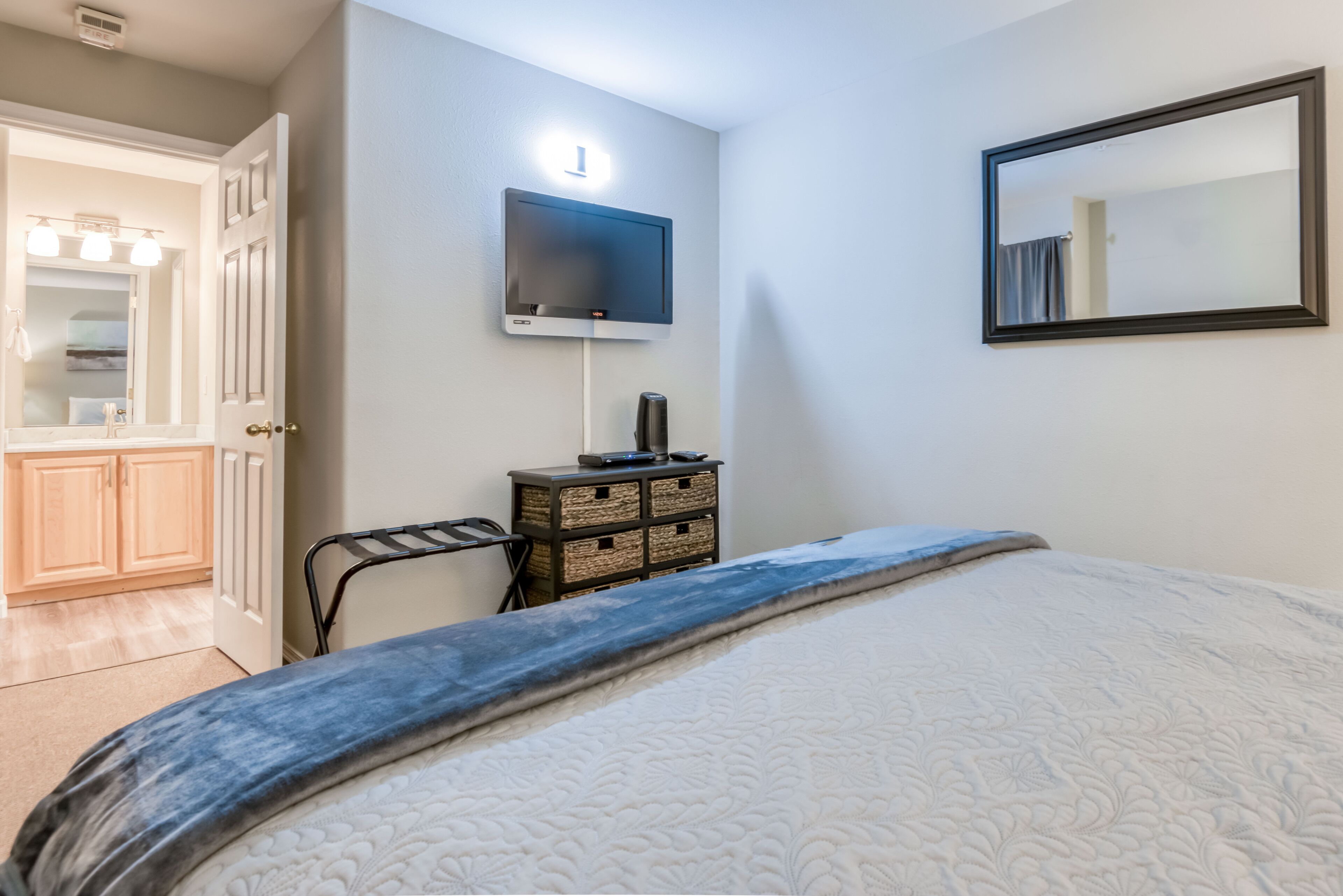 A bedroom with a bed, a dresser, a television, and a mirror.