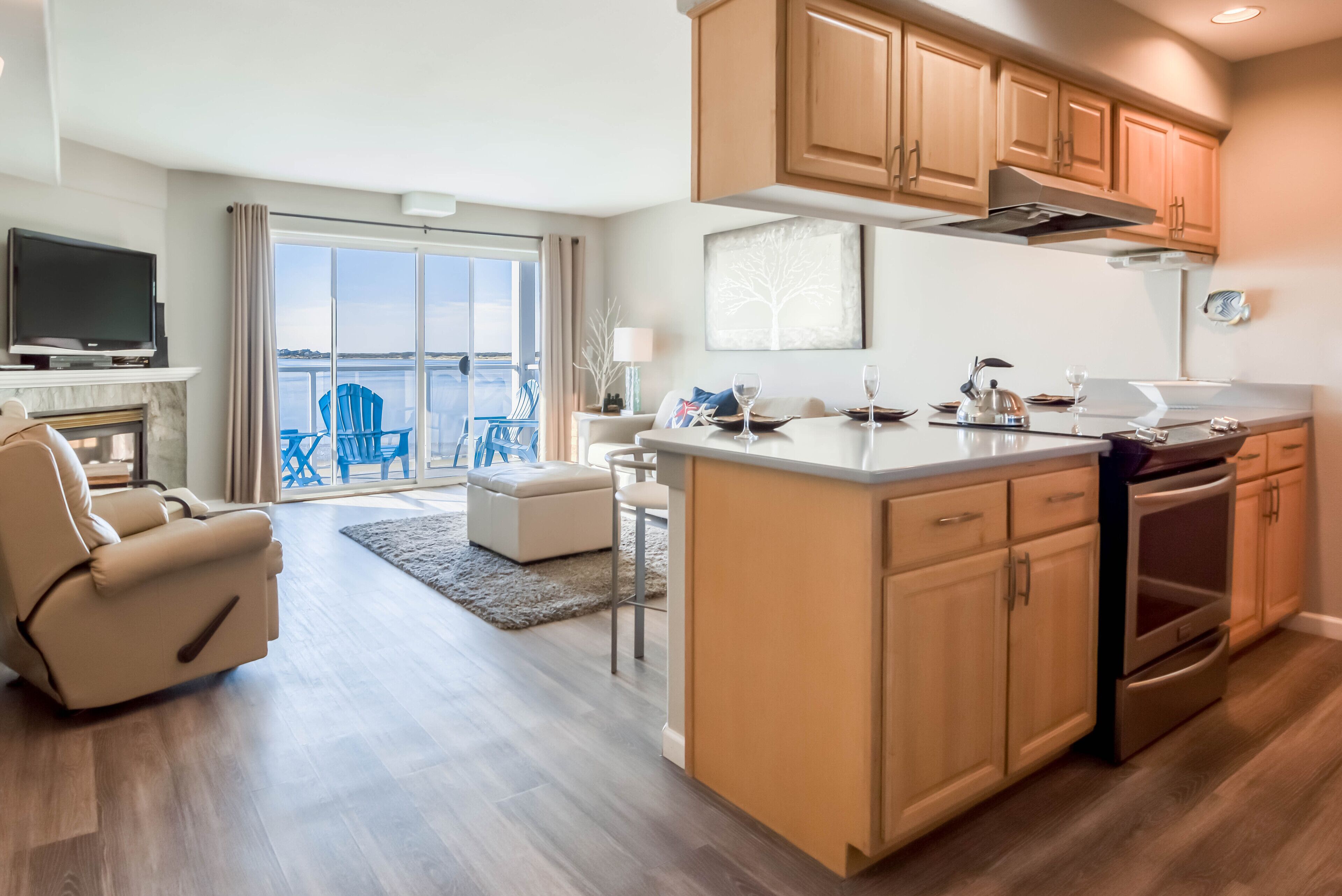A modern kitchen with wooden cabinets, a central island, and a dining area with a view of the water.