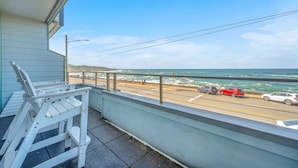 A balcony with a view of the ocean and a road with cars.