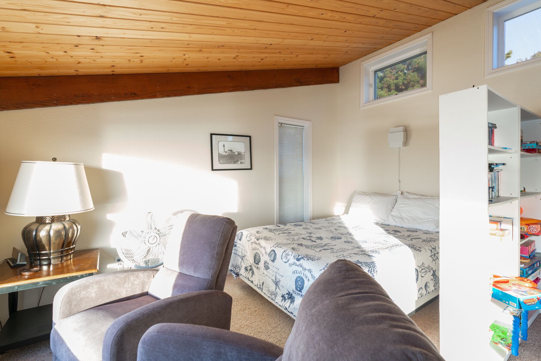 Una camera da letto con un letto, una sedia, una scrivania con una lampada, una finestra e una libreria.