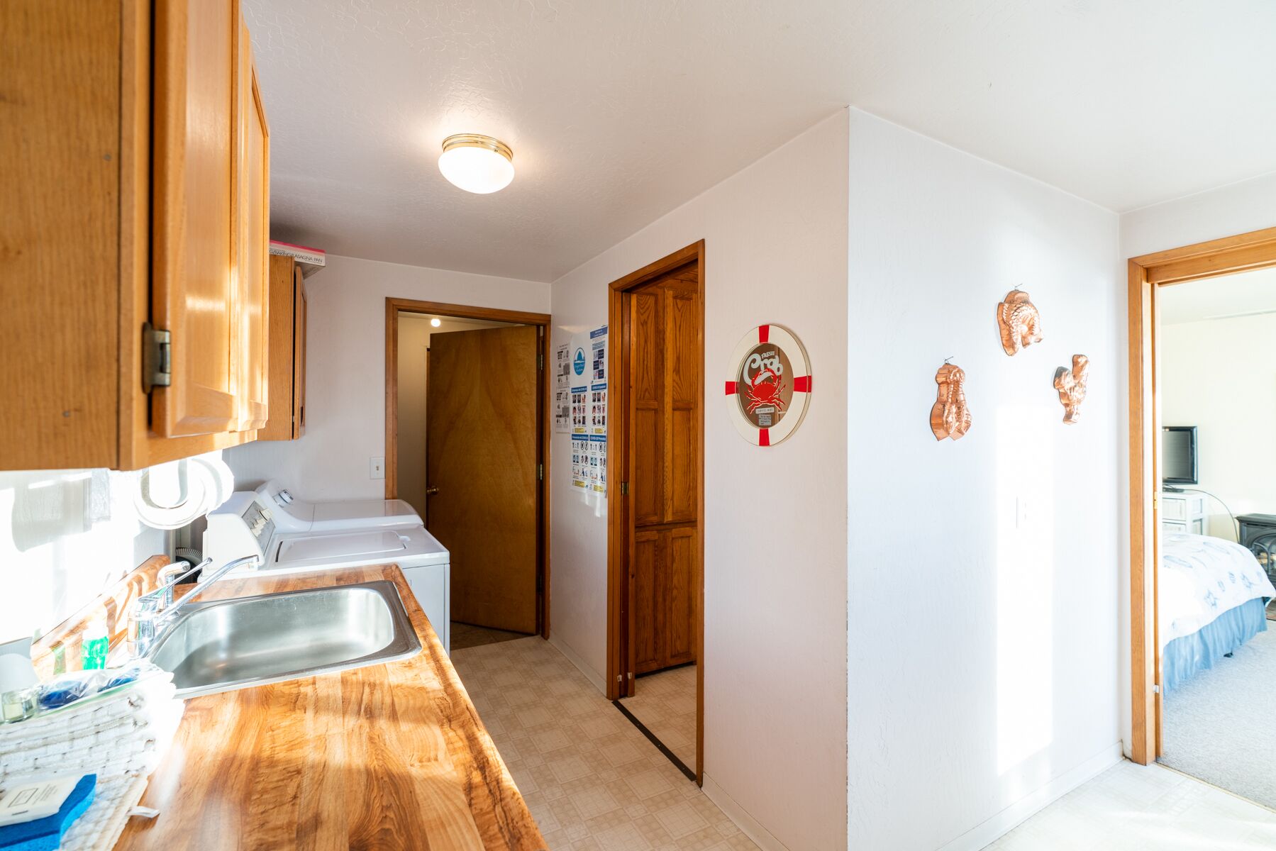 A compact kitchen with wooden cabinets, a built-in washing machine, a sink, and a small countertop.