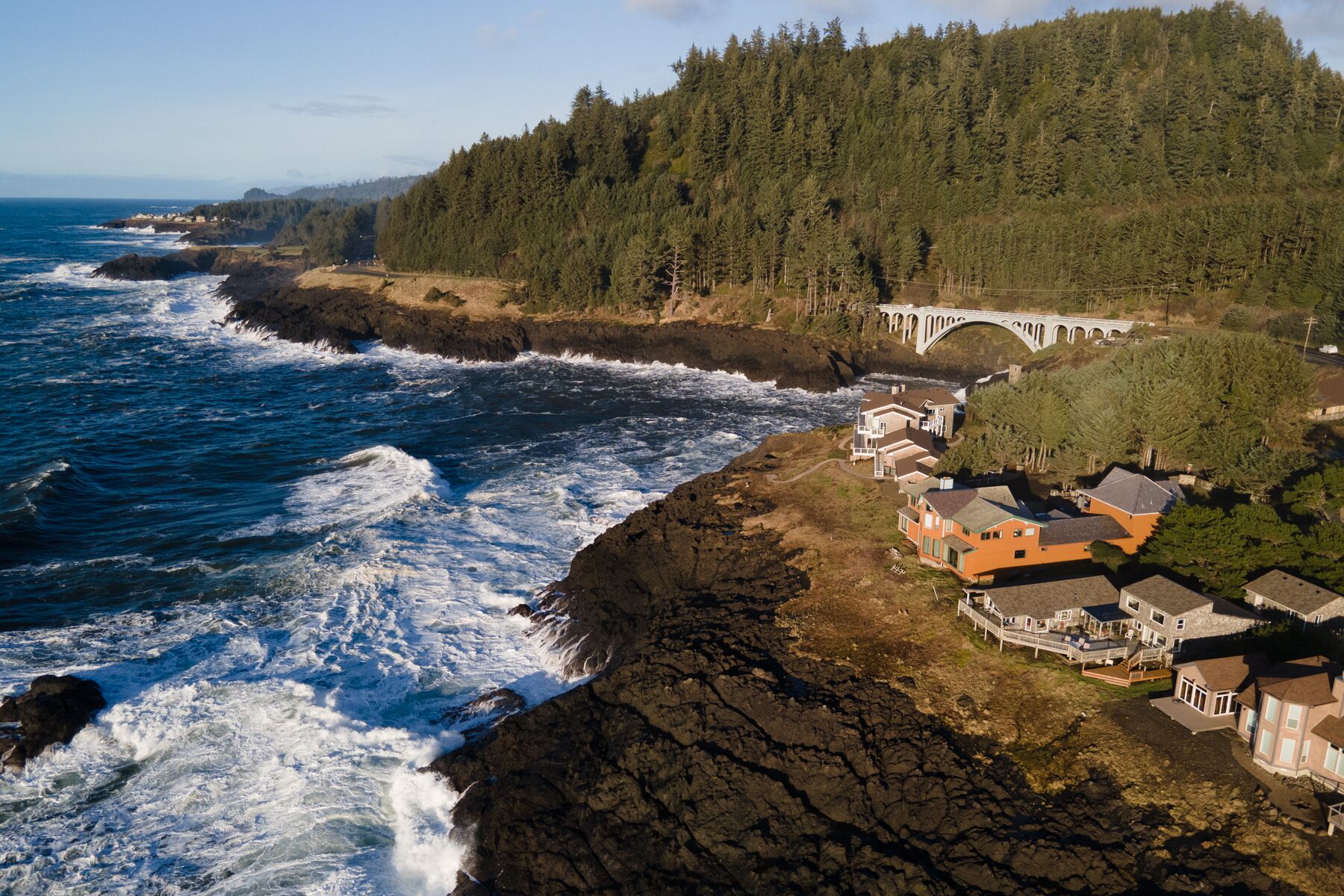 Une propriété située sur la côte, avec un rivage rocheux, un pont et une colline boisée.