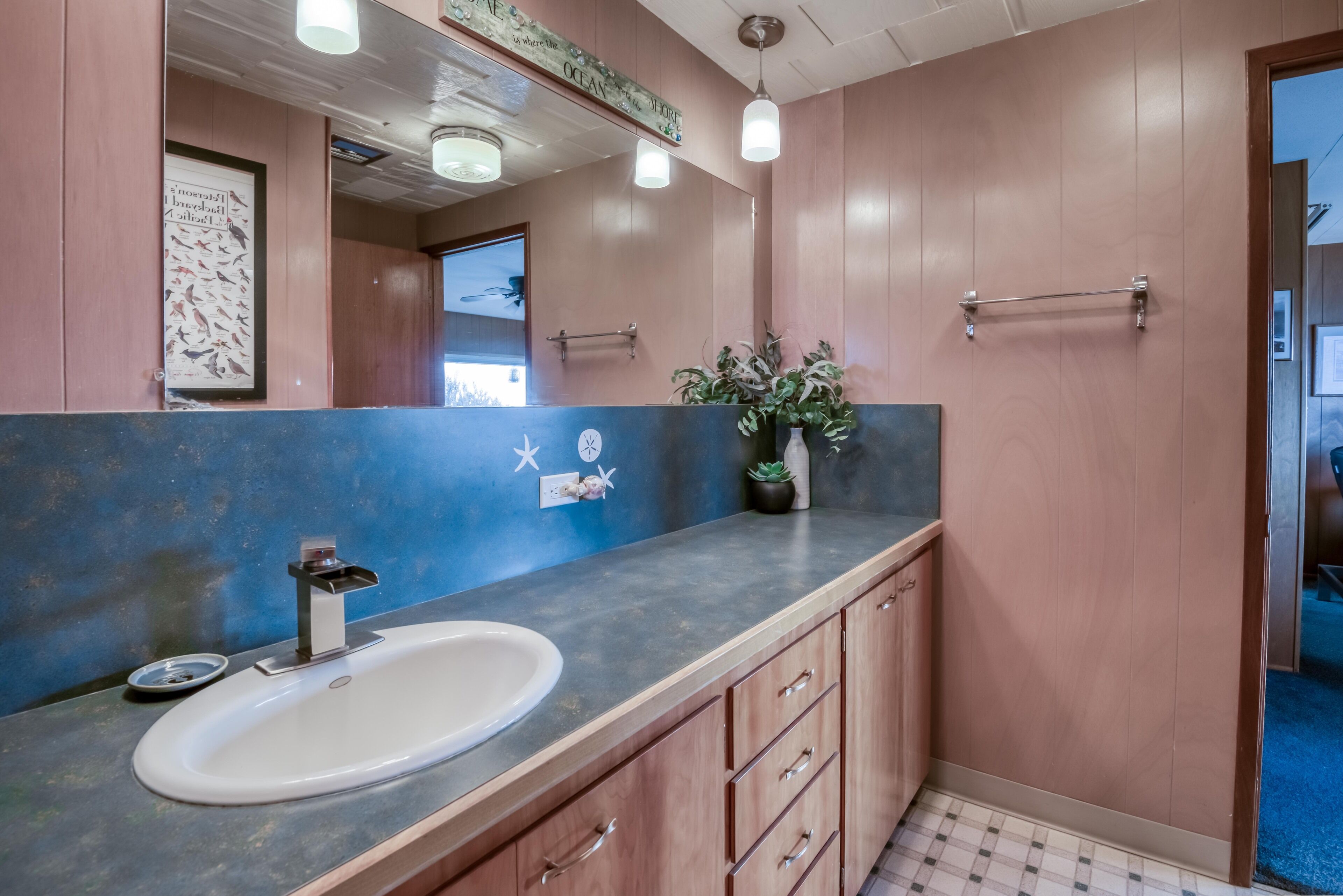 A bathroom with a sink, mirror, towel rack, and a potted plant.