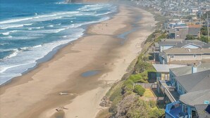 A coastal town with a sandy beach, houses along the shore, and a hilly backdrop. - Beautiful home with ocean views, easy beach access and wheelchair accessible (Lincoln City)