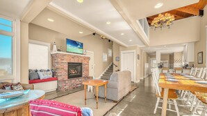 A spacious living area with a fireplace, a dining table, and a staircase leading to another level. - Beautiful home with ocean views, easy beach access and wheelchair accessible (Lincoln City)