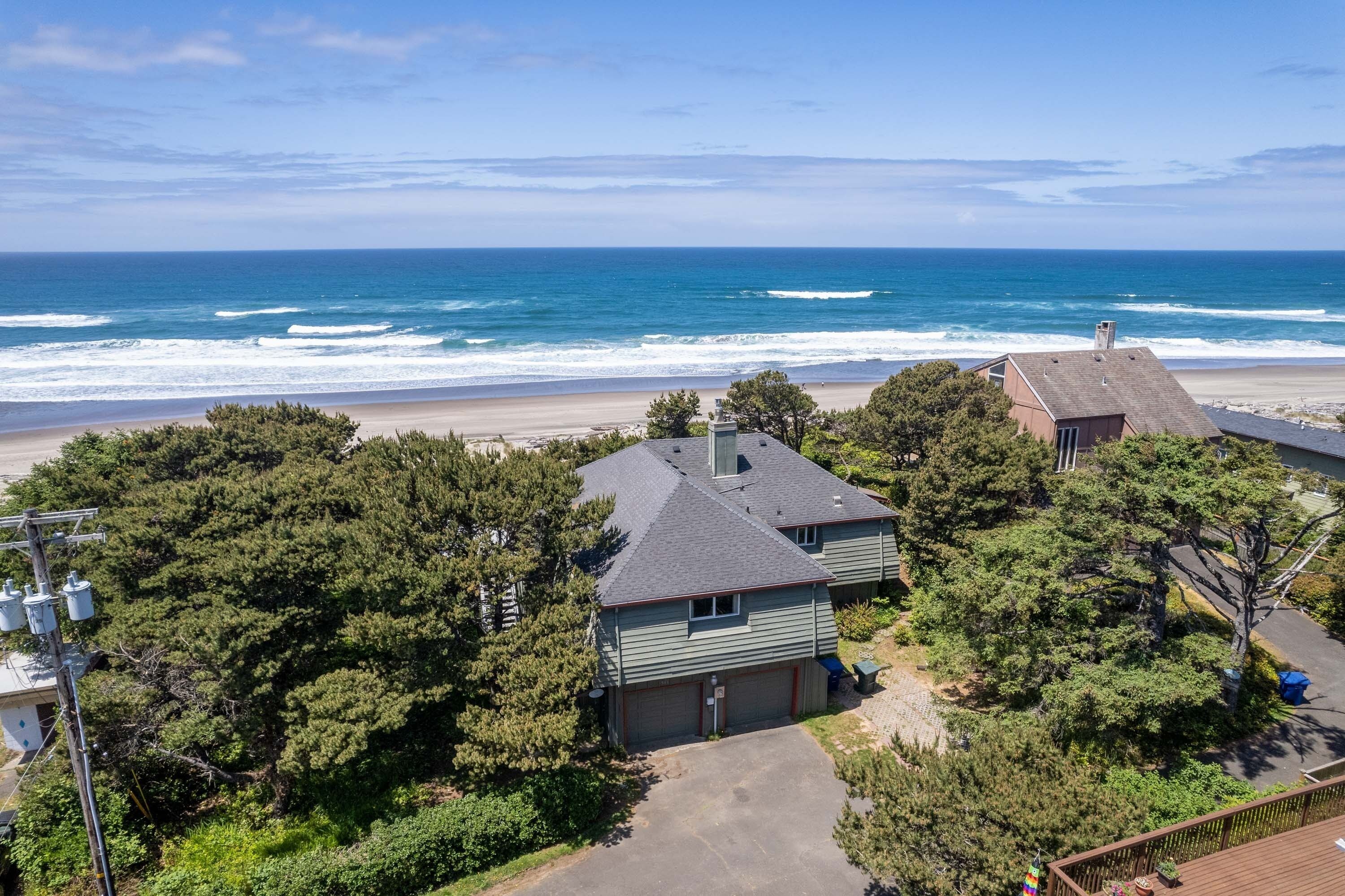 A coastal residential area with houses, a beach, and a clear sky.