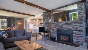 Una sala moderna con chimenea de piedra, un televisor sobre un mueble de madera y un sofá.