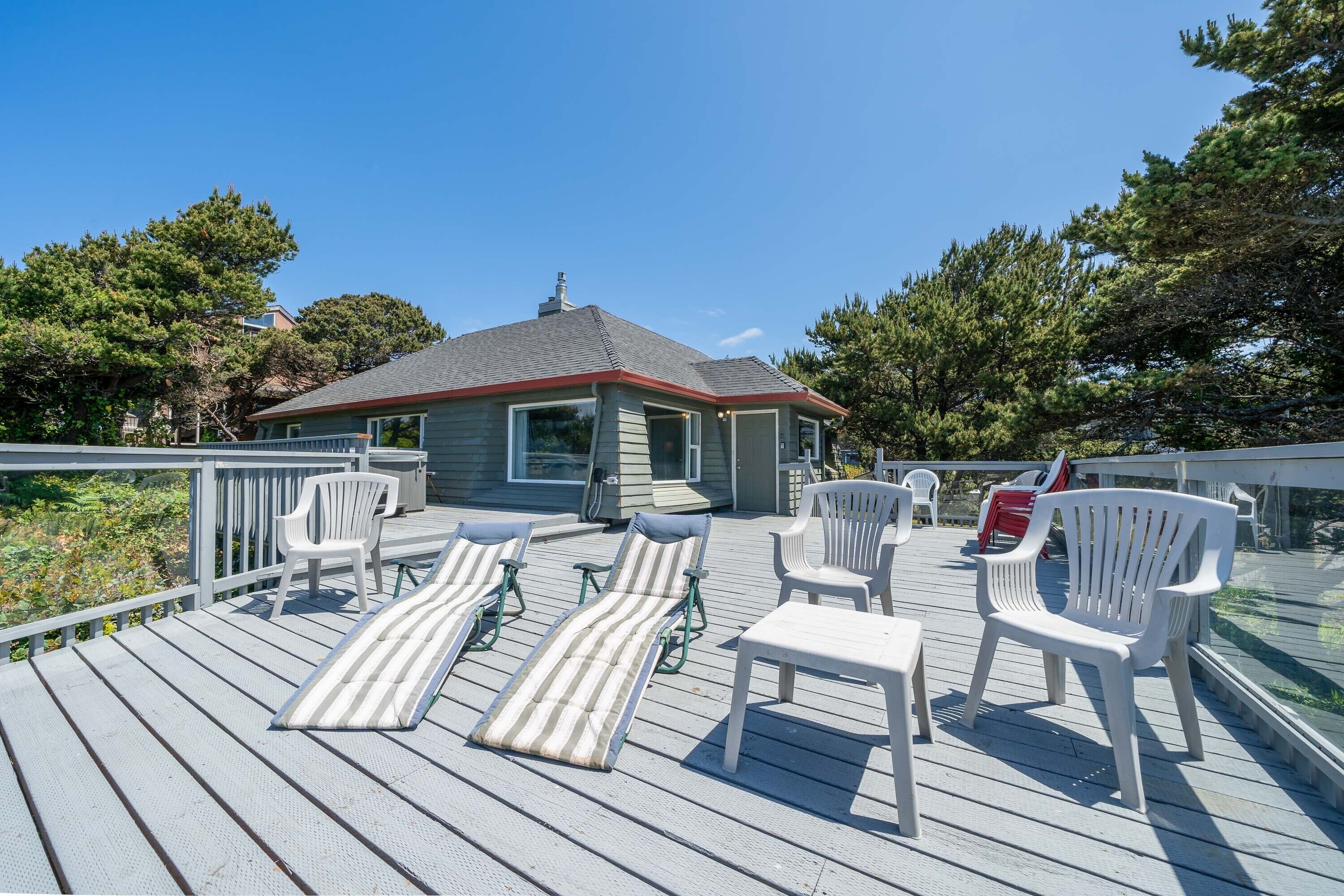 A deck with lounge chairs, a small building, and a railing.