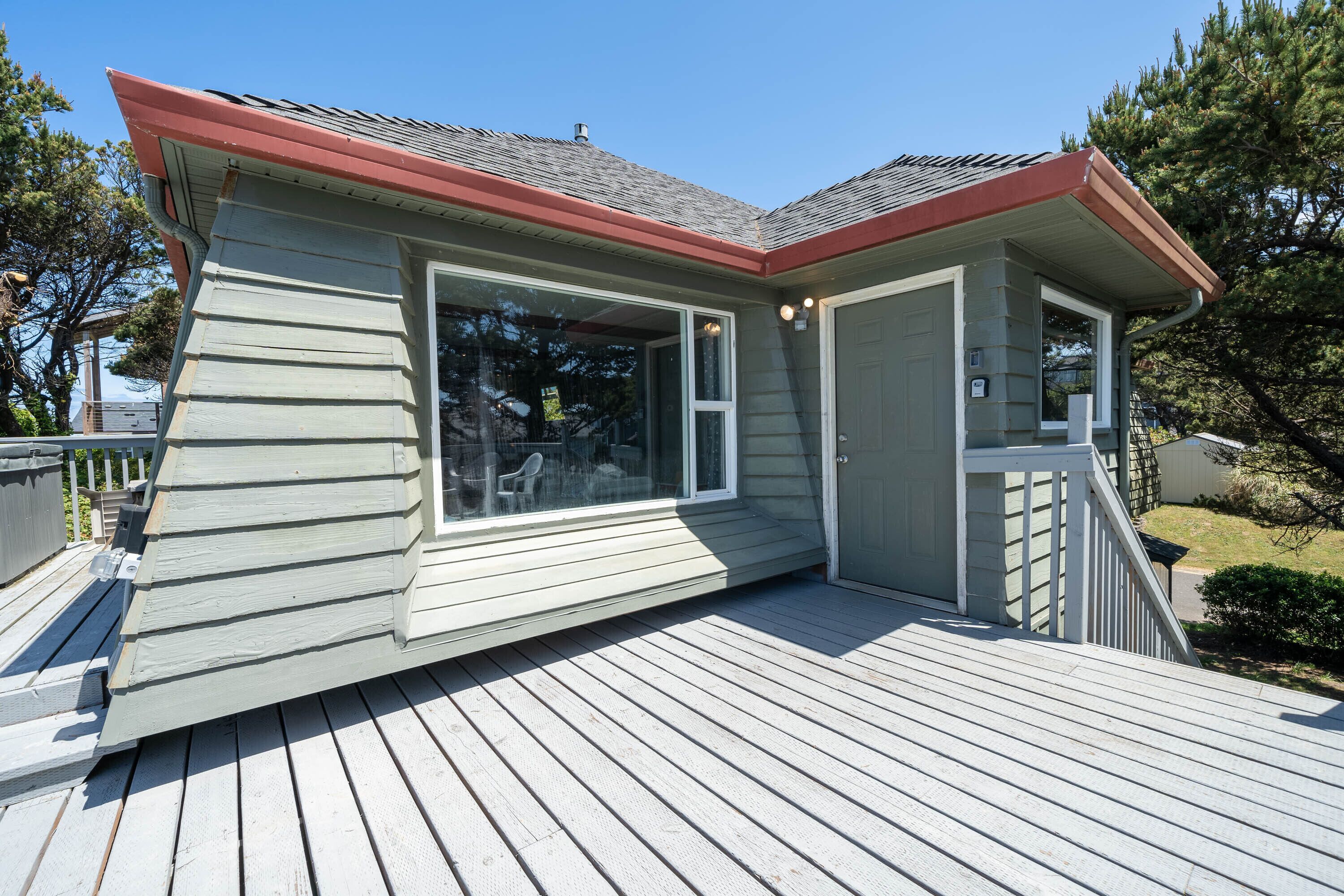 A house with a deck, a large window, and a door.