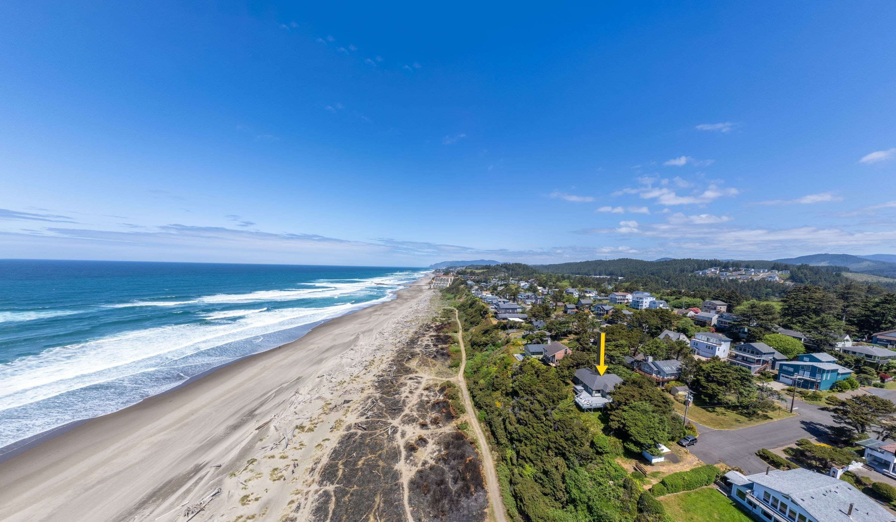 A coastal residential area with a beach, houses, and a clear sky.