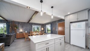 Una cocina moderna con una isla grande, armarios blancos e iluminación colgante.