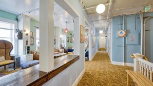 A hotel hallway with a patterned carpet, wooden benches, and a laundry sign. - HI San Francisco Downtown Hostel (San Francisco)