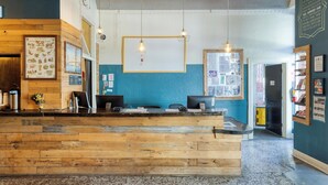 A reception desk with wooden panels, two pendant lights, and a bulletin board with various notices. - HI San Francisco Downtown Hostel (San Francisco)