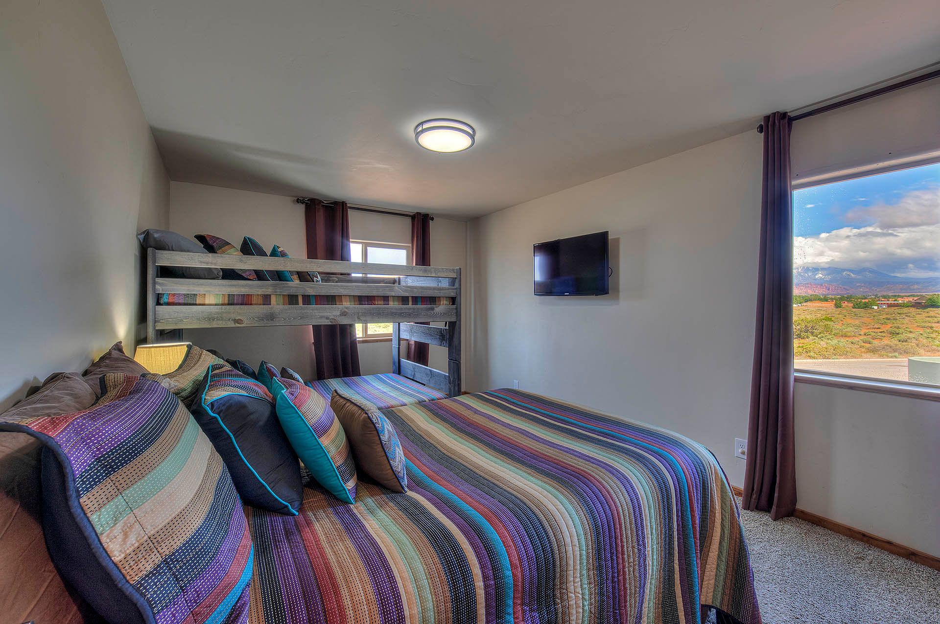 Une chambre avec un lit superposé, une télévision et une fenêtre donnant sur un paysage.