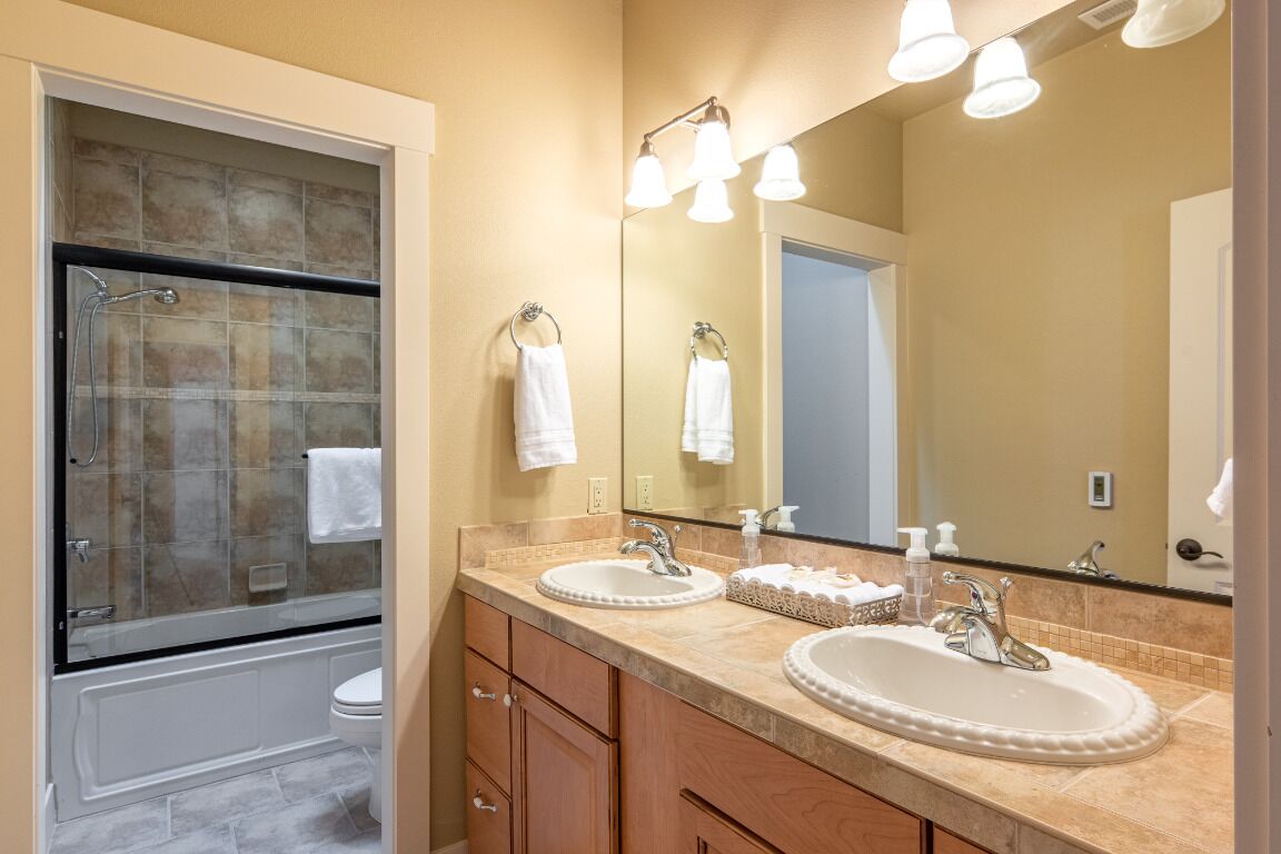 A modern bathroom with a glass-enclosed shower, two sinks, and a large mirror.