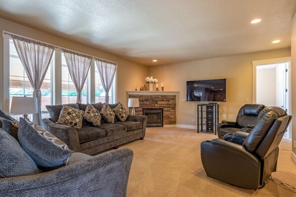 A living room with a sofa set, a recliner, a fireplace, and a flat-screen TV.
