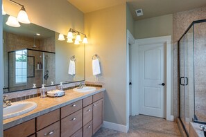 A bathroom with a double sink vanity, a large mirror, and a glass shower enclosure.