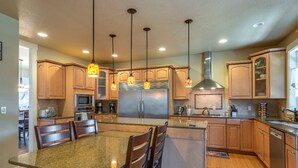 A modern kitchen with granite countertops, stainless steel appliances, wooden cabinets, and pendant lighting. - Brookwood Manor (5 Bedroom, 14 Guests) (Hillsboro)
