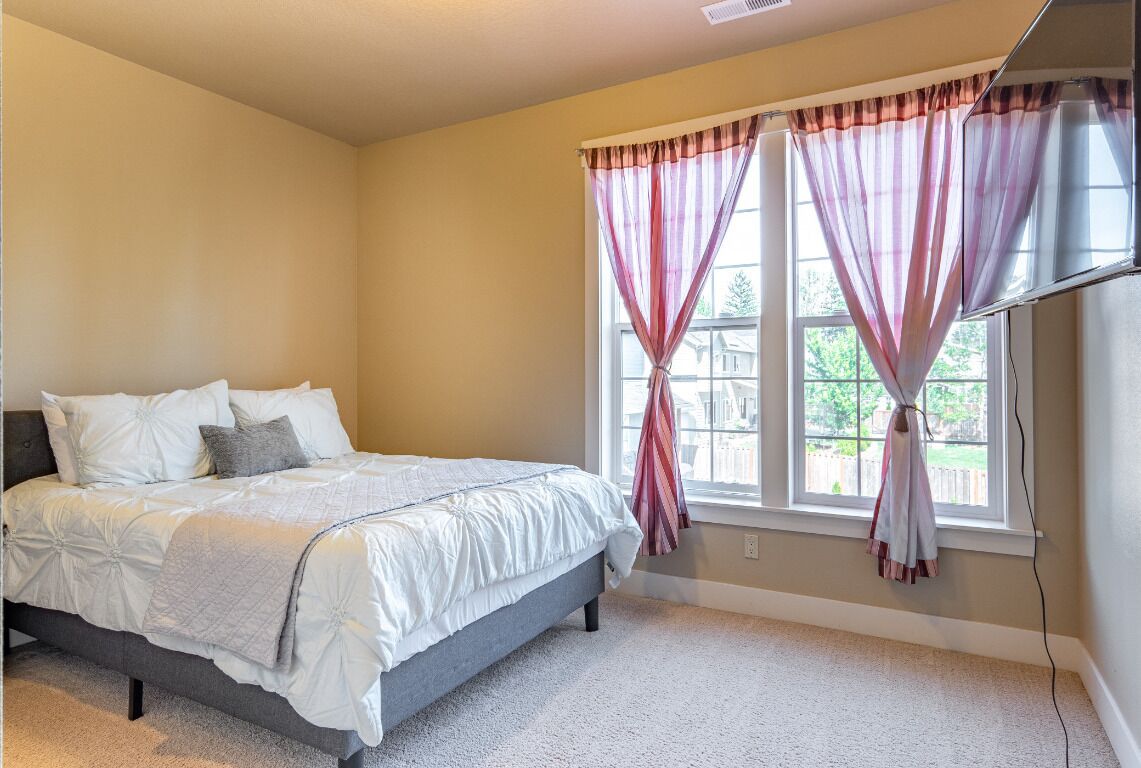 A bedroom with a bed, curtains, and a window.