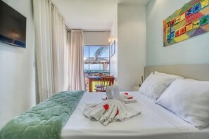 Habitación de hotel con una cama, un televisor, vistas al exterior y una obra de arte llamativa en la pared.