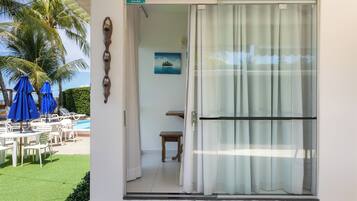 Quarto com porta de correr de vidro, uma mesinha, um banco e um quadro na parede.