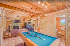 Relax in this cabin-style room with a pool table, fireplace, and comfortable seating area.