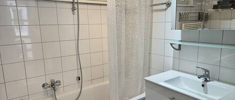 Un baño moderno con bañera, ducha, lavamanos y espejo.