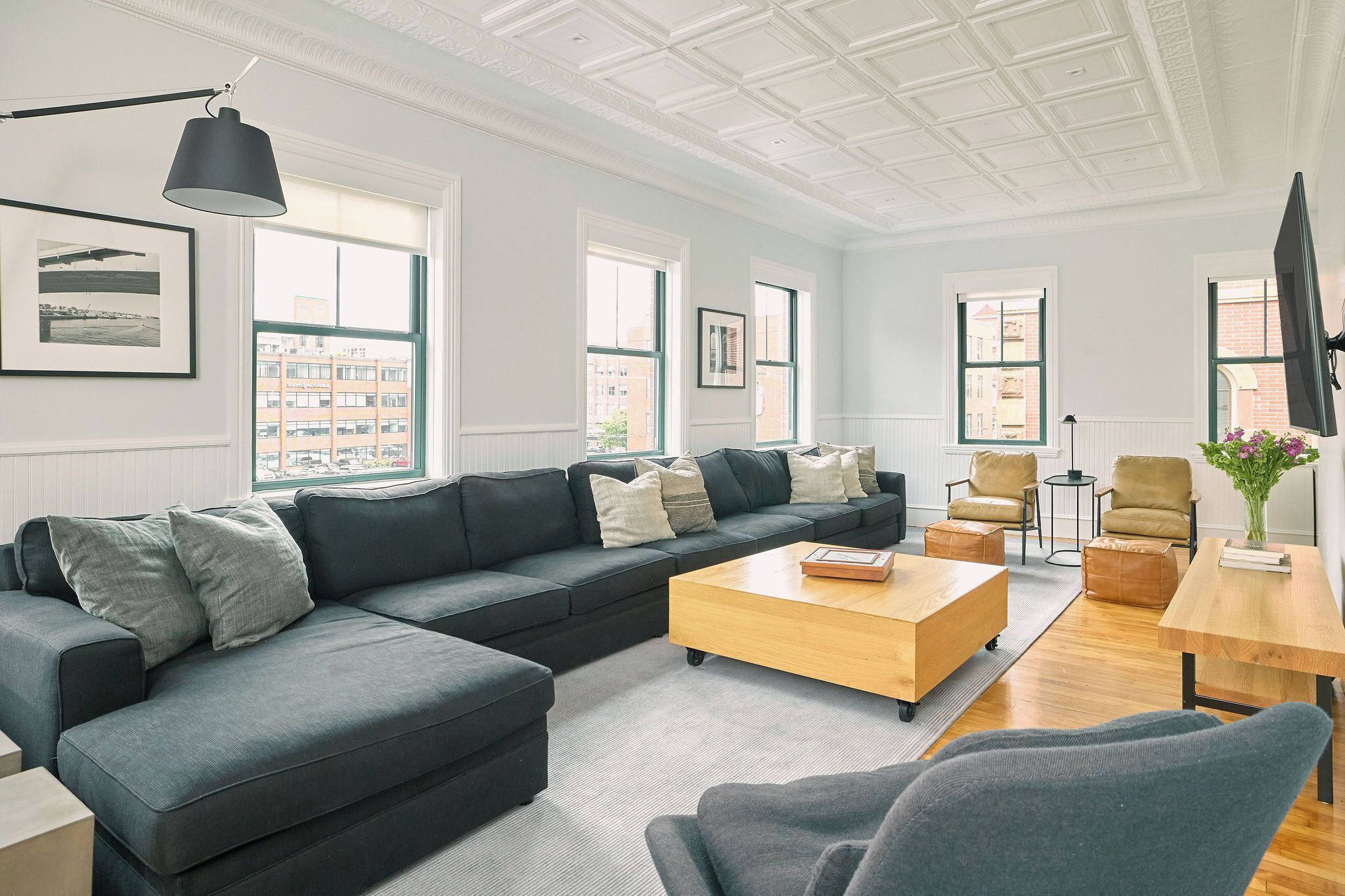 A modern living room with a sectional sofa, a wooden coffee table, and a TV on a stand.