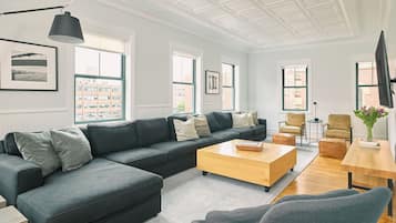 A modern living room with a sectional sofa, a wooden coffee table, and a TV on a stand.