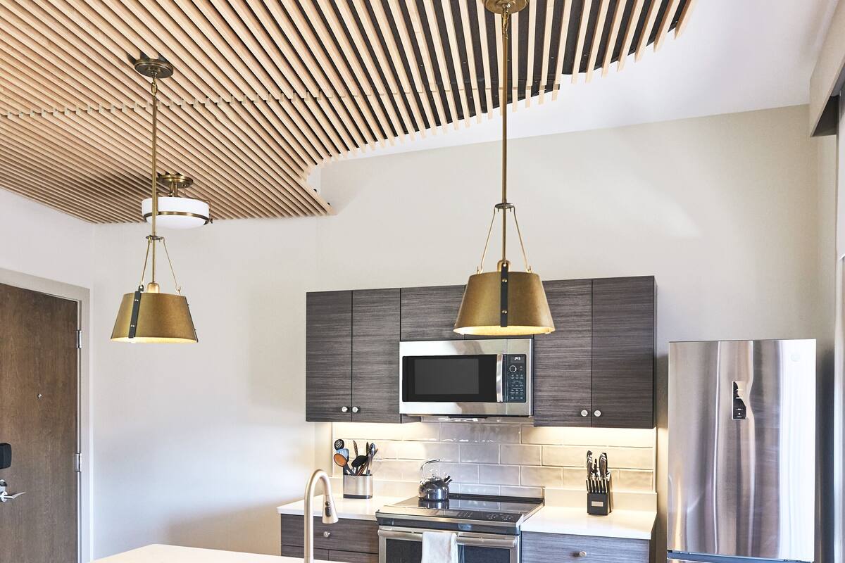 A modern kitchen with a central island, stainless steel appliances, and wooden bar stools.