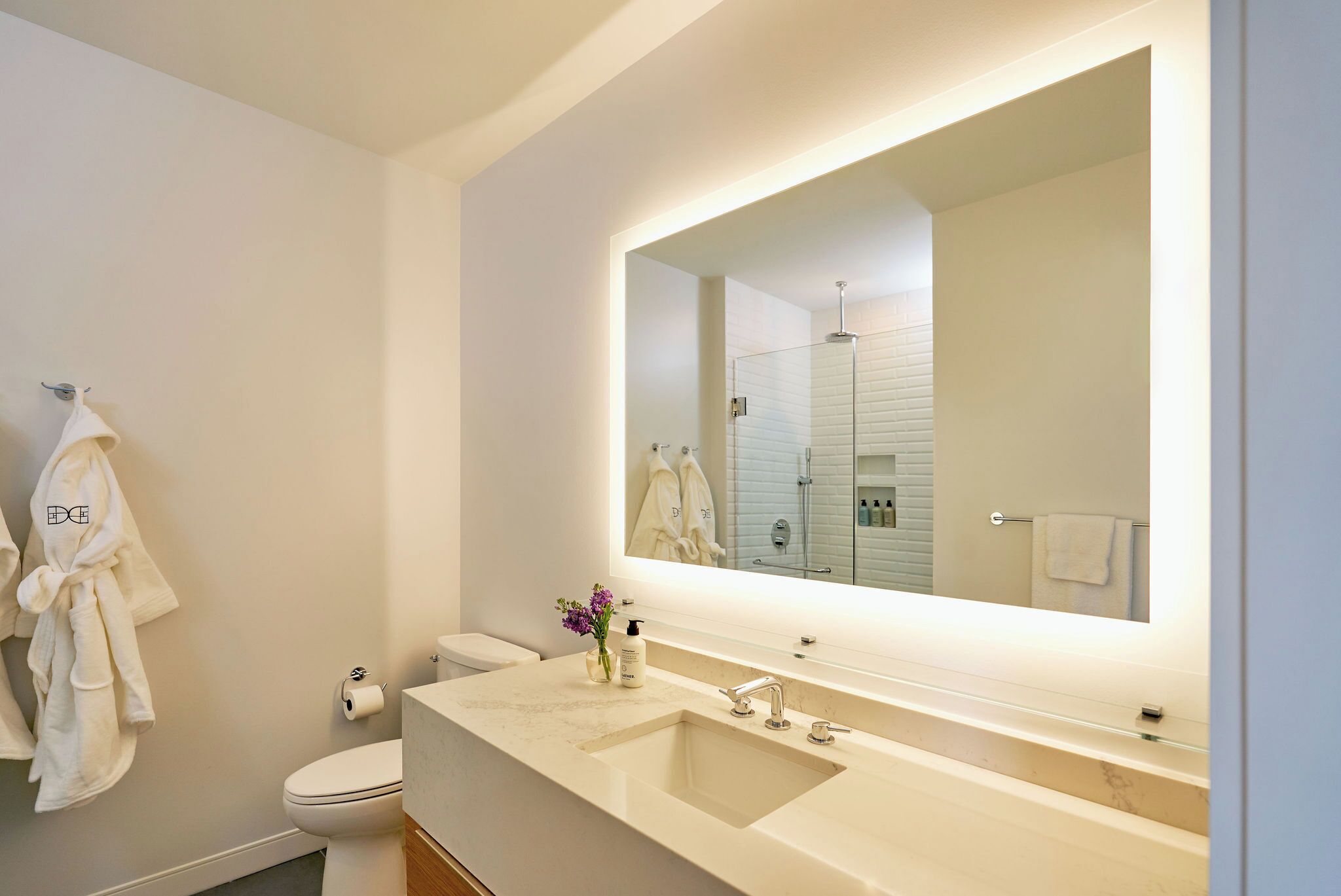 Un bany modern amb un mirall gran, un lavabo i un vàter.