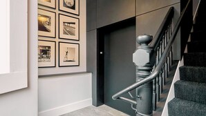Eine Treppe mit Handlauf, eine Wand mit gerahmten Bildern und eine Tür mit Griff.