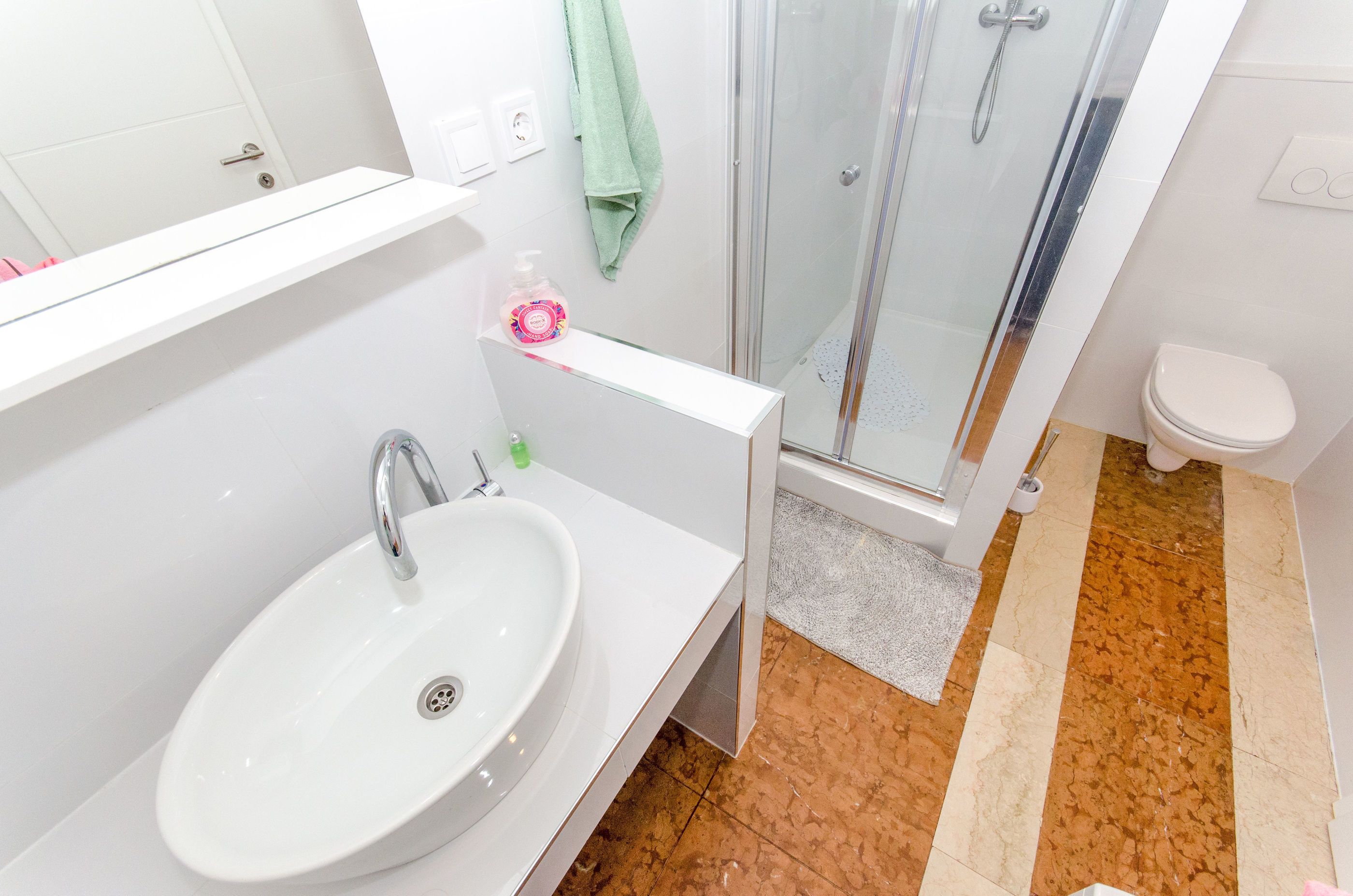 A bathroom with a white sink, a glass shower enclosure, and a toilet.