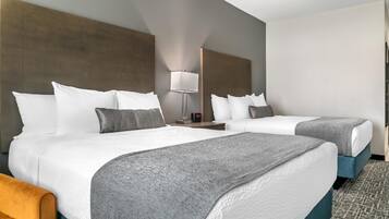 A hotel room with two beds, a nightstand, a lamp, and a clock.