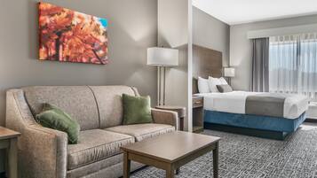 Une chambre d’hôtel avec un canapé, une petite table, un lit avec un matelas bleu et un tableau au mur.