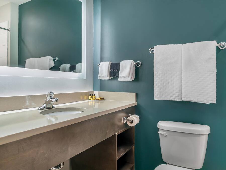 A bathroom with a sink, mirror, towel rack, and toilet.