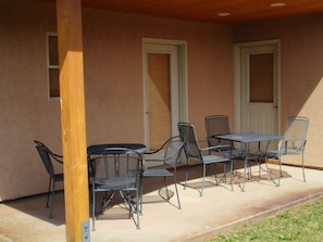 An outdoor patio with a table and chairs, a wooden post, and a door with a window. - Tierra Del Sol 2 by MoabCondos4Rent (Moab)