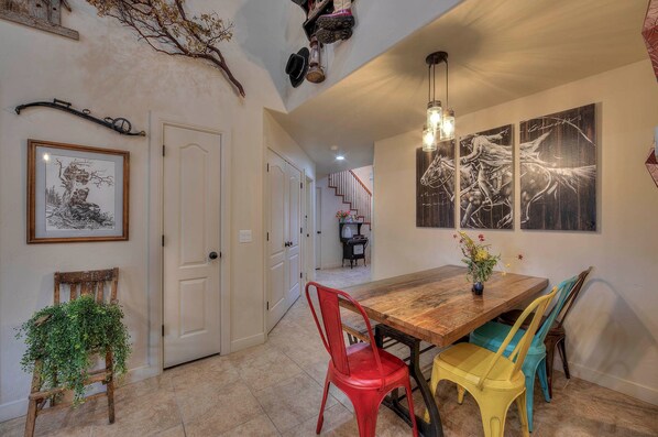 A dining area with a wooden table, colorful chairs, and artwork on the walls.