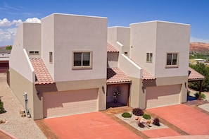 Une maison moderne à deux étages, dotée d’un garage, d’un petit jardin et offrant une vue dégagée sur le paysage environnant.