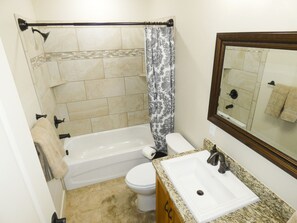 A bathroom with a bathtub, toilet, sink, and a shower curtain.