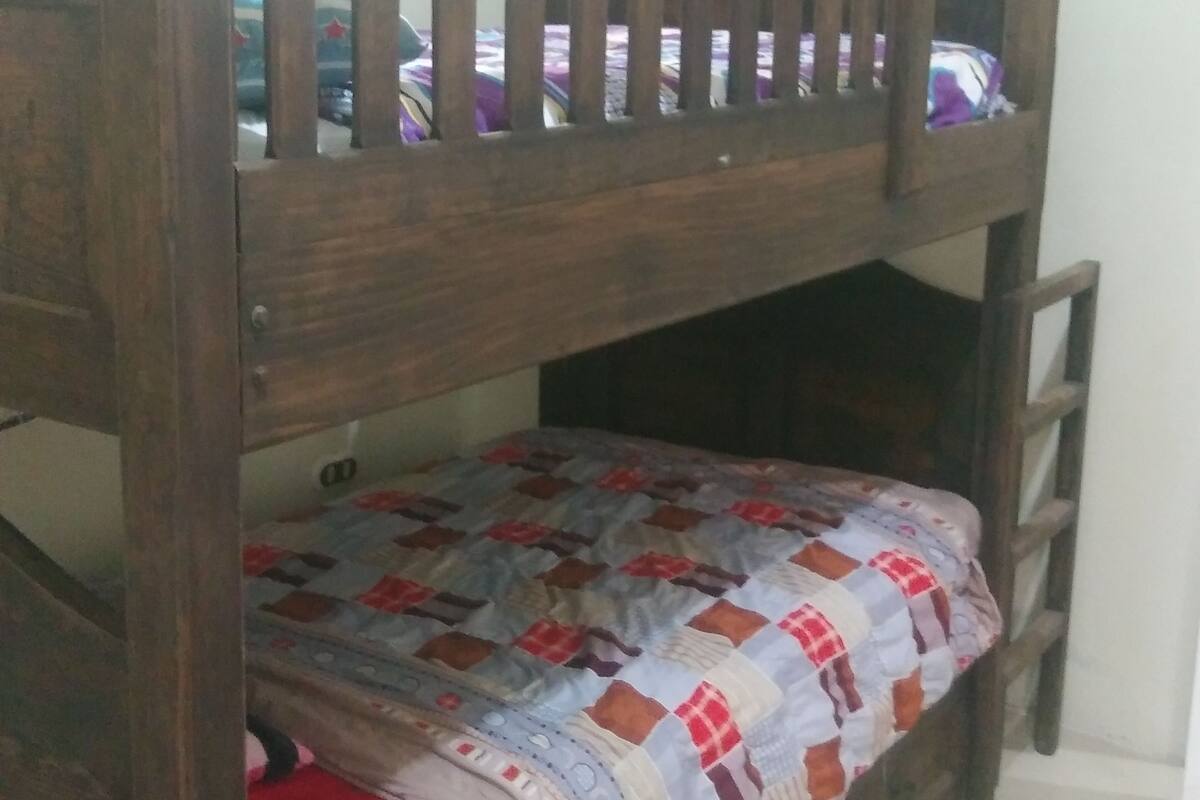 A bunk bed with a wooden frame and a quilted bedspread.