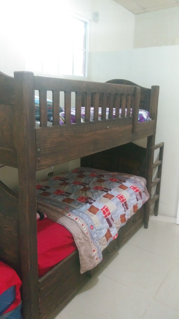 A bunk bed with a wooden frame and a quilted bedspread. - Green Jungle Hotel y Restaurante (Flores)