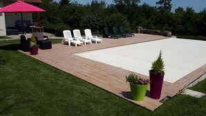 Un giardino sul retro con piscina, sedie a sdraio e zona barbecue.