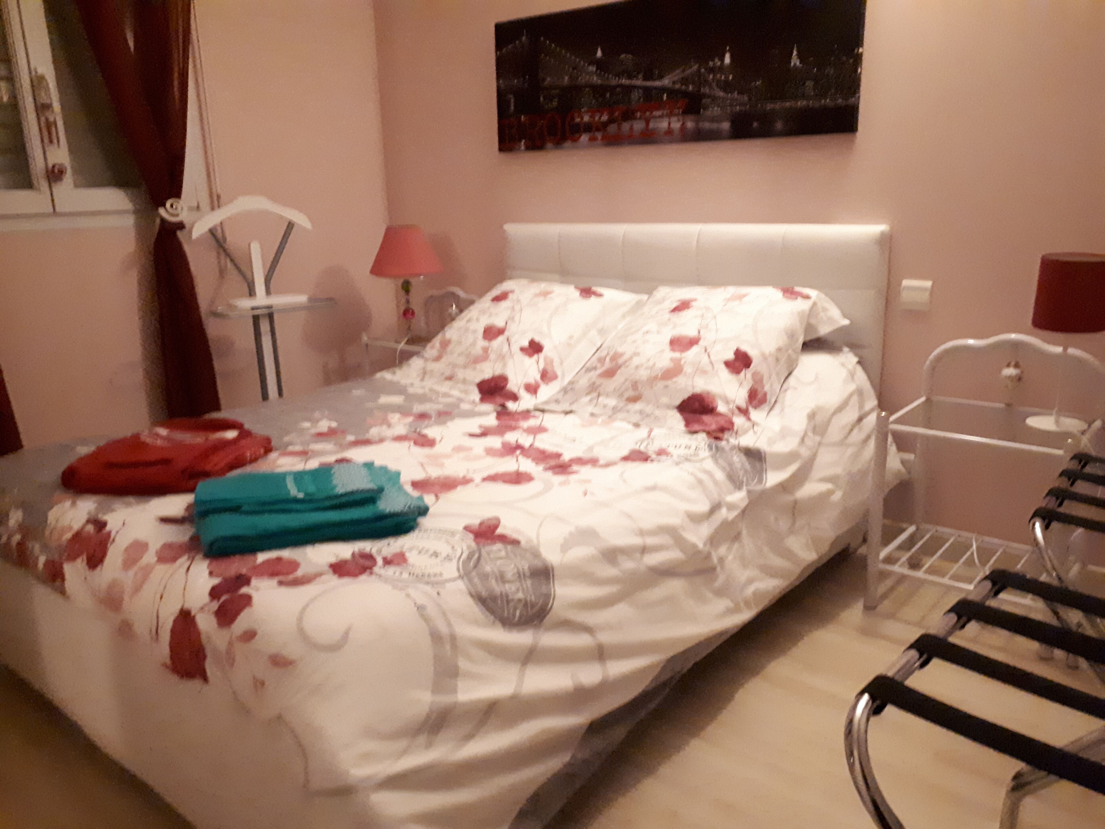 A bedroom with a bed, a nightstand, a lamp, and a chair.